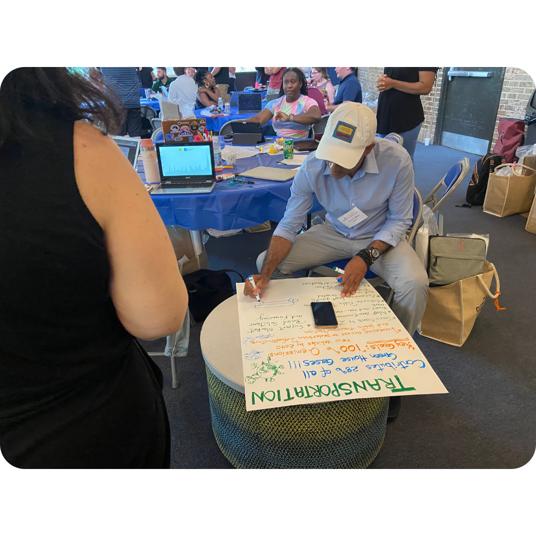 Participants collaborating in a hands-on workshop, brainstorming and writing ideas on a large poster.