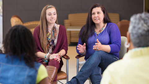 Educators seated in a small group discussion, engaged in a professional development conversation in a meeting setting